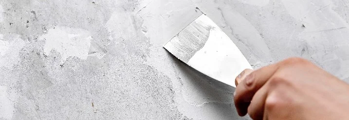 Hand spachtelt graue Wand